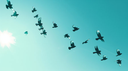 A flock of birds soaring gracefully across a clear blue sky, their wings outstretched in flight.の素材