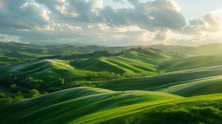 Sunlit clouds casting soft shadows on rolling green hills in the countrysideの素材
