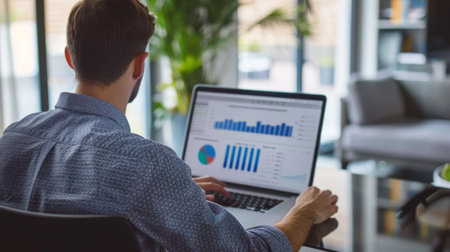 A businessman analyzing financial charts and graphs on a laptop during a strategy meeting in a modern office.の素材