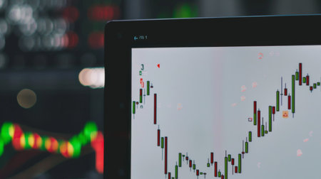 A stock market graph showing a steady rise, displayed on a large office monitor.の素材