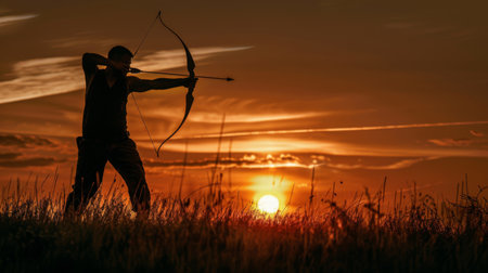 A silhouette of an archer practicing with a bow and arrow at sunsetの素材