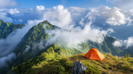 A tent pitched on a mountain ridge with a view of clouds rolling over nearby peaksの素材