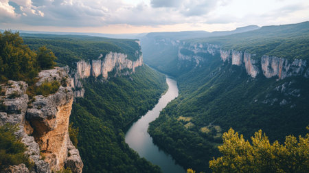 A high-altitude view of a winding river cutting through a mountain range, with the steep cliffs and dense forests creating a dramatic natural scene.の素材