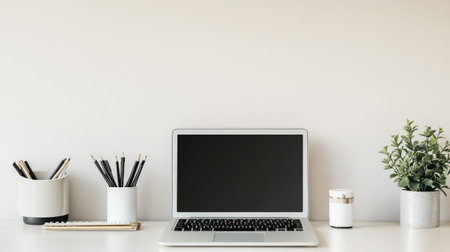 A close-up of a minimalist workspace with a clean desk, a sleek laptop, and a few neatly arranged office supplies, set against a light, neutral background.の素材
