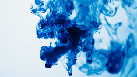 Blue ink dropping into clear water, creating swirling patterns and abstract shapesの素材