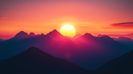 Close-up of a mountain range silhouetted against a vibrant sunset, with the sun dipping behind the peaksの素材