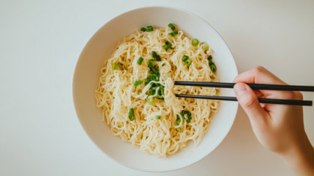 A person enjoying a bowl of noodles, with a pair of chopsticks in hand, with a clean white background emphasizing the simplicity and pleasure of the meal.の素材