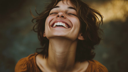 Portrait of a woman laughing joyfully with her eyes closed and head tilted back, capturing the genuine emotion and happiness in her expression.の素材