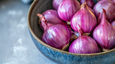 A close-up of shallots in a bowl, with their skins slightly cracked and revealing the purple flesh, set against a clean background to emphasize their freshness.の素材