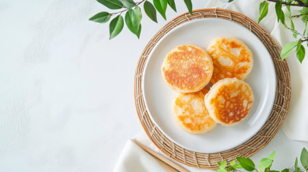 A clean and simple presentation of Thai sweets, including sweet coconut pancakes and mung bean cakes, on a white plate with a white backdropの素材