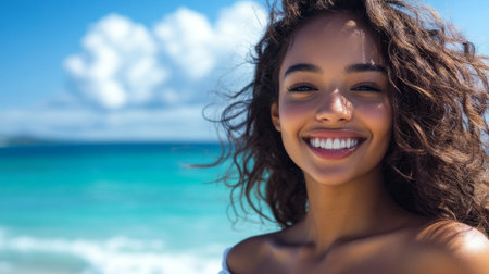 A beautiful woman with a radiant smile, enjoying a day at the beach, with the ocean and blue sky in the background.の素材