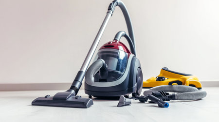 A vacuum cleaner with a detachable hose and various attachments, neatly arranged on a white floor, highlighting its versatility and design.の素材