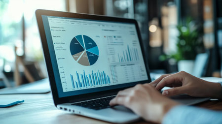 A professional analyzing a financial pie chart on a laptop screen, with charts showing budget allocations and expenses, in a modern office environment.の素材