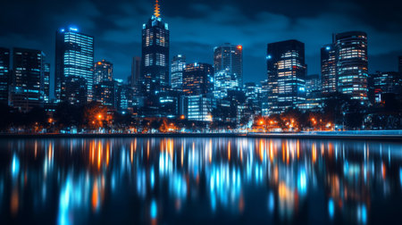 A nighttime cityscape with illuminated skyscrapers standing tall, their lights reflecting on nearby waterways, creating a stunning urban landscape.の素材