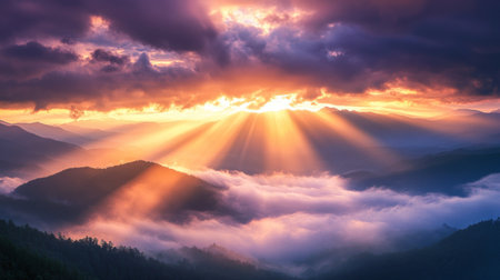 A dramatic shot of sunbeams breaking through the clouds, casting light and shadow across a vast mountain range. The sky is painted in shades of orange, pink, and purpleの素材