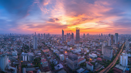 Stunning panoramic view of a city skyline at sunset, showcasing vibrant colors and a blend of modern architecture against a dramatic sky.の素材