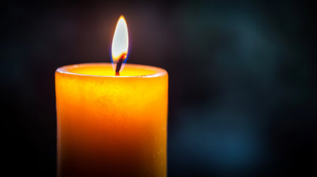 A single orange candle burns brightly against a dark background, creating a warm and inviting atmosphere. Ideal for themes of relaxation, meditation, and tranquility.の素材