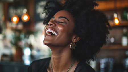 A joyful woman with curly hair laughs heartily in a cozy cafの素材