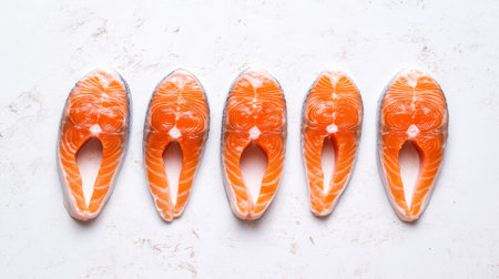 High-quality raw salmon steak pieces neatly arranged, showcasing their vibrant color and fresh texture, perfect for culinary inspiration and healthy meal preparations.の素材