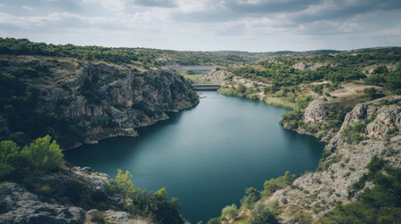 This image captures a tranquil river winding through lush green hills under a cloudy sky, creating a perfect setting for nature lovers and adventurers.の素材