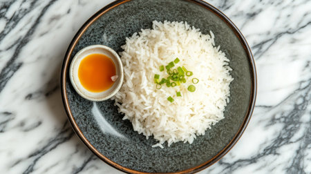 A beautiful presentation of steaming white rice garnished with chopped green onions served with a small bowl of sauce on a marble surface. Perfect for culinary themes.の素材