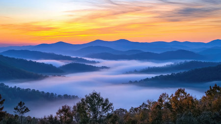A silhouette of mountains against a colorful sunrise sky, with layers of clouds and mist creating a dramatic and serene scene, perfect for nature enthusiastsの素材