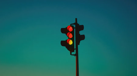 A diagonal view of a traffic light with all signals illuminated, set against a clear blue sky, highlighting the technology behind traffic managementの素材