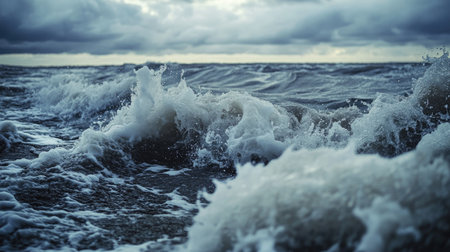 Close-up of powerful waves hitting the shore during a storm, with dramatic sky and turbulent watersの素材