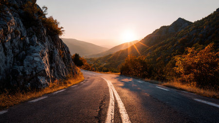 Captivating image of a curving road winding through a picturesque mountain valley during sunset, showcasing vibrant foliage and stunning natural beauty.の素材