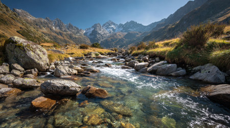A stunning view of a mountain stream flowing over rocky terrain, surrounded by majestic peaks under a bright blue sky, showcasing the beauty of nature.の素材