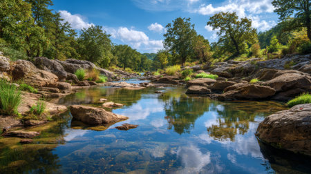 A tranquil river flows gently through a rocky landscape, with clear waters reflecting the blue sky and lush trees, creating a peaceful atmosphere for nature lovers.の素材