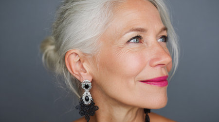 A captivating portrait of an elderly woman with striking silver hair, showcasing her elegance and charm through bold earrings and a warm smile against a soft background.の素材