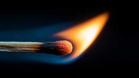 A captivating close-up image of a matchstick igniting, featuring a bright orange flame accentuating the contrast against a dark background, perfect for evoking warmth and energy.の素材