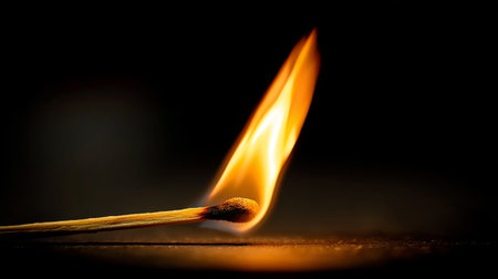 This close-up image shows a matchstick igniting with a vibrant flame, creating a striking visual against the dark background, illustrating the beauty of fire and light.の素材