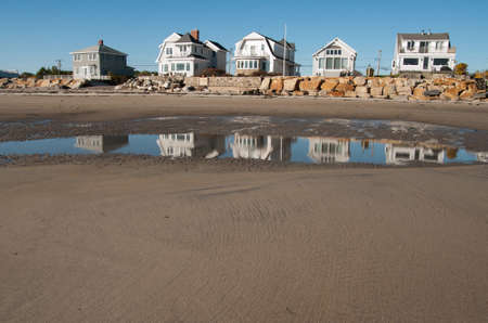 A row of cottages along the beach reflected in the water at low tideの写真素材