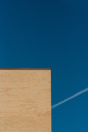 Jet trail behind yellow brick highrise buildingの写真素材