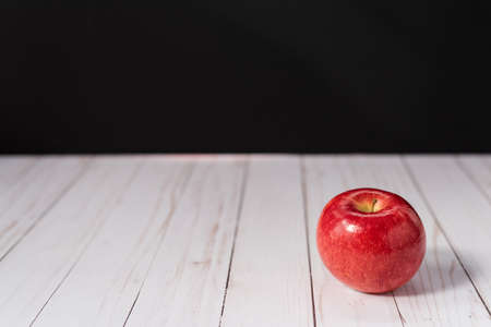 One red apple on a whitewashed wood countertop with a black backgroundの写真素材