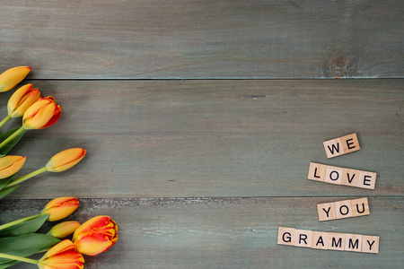 Colorful tulips on weathered green planks. Tile letters with sentiment for Mother's Day.の写真素材
