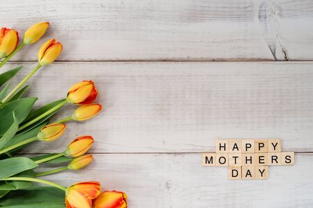 Yellow and red tulips on whitewashed wood with Mother's Day message in letter tilesの写真素材