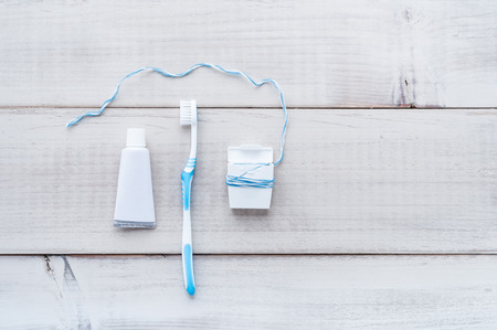 Toothbrush, tube of toothpaste and dental floss on a weathered wood backgroundの写真素材
