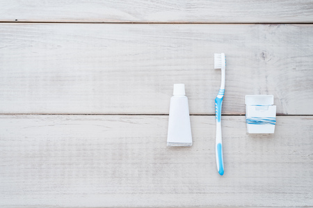 Toothbrush, tube of toothpaste and dental floss on a weathered wood backgroundの写真素材