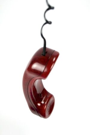 A red telephone receiver hanging from its cordの写真素材
