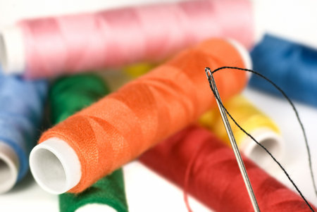 Differing colored cotton with a threaded needle in the foreground