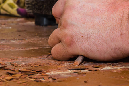 Strong working hands doing repairs. In the hands of a screwdriver. We rip off the paint off the...
