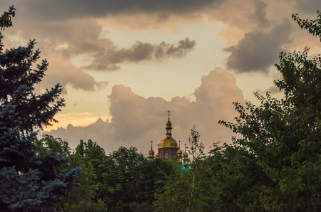 Beyond the branches of the trees there is a golden cross on the dome of the church.の写真素材