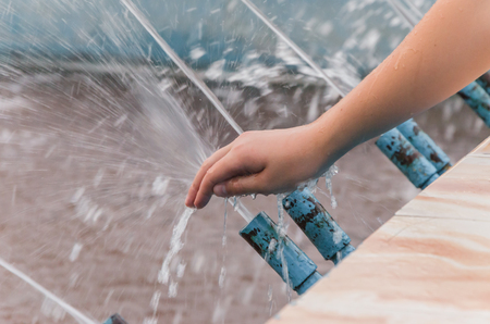 Children's hand closing a stream of fountain waterの写真素材