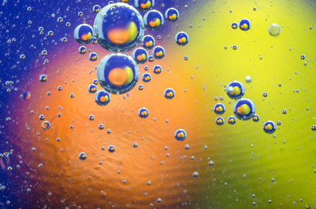 Oil bubbles in the water over a colored background.