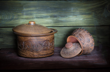 Empty clay pots on a wooden background illuminated in the dark with a flashlight.