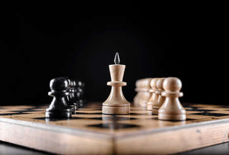 Wooden chess pieces on a wooden board with varied light.の写真素材