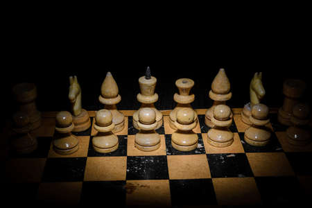 Wooden chess pieces on a wooden board with varied light.の写真素材
